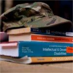 camouflage hat with brim atop a stack of books